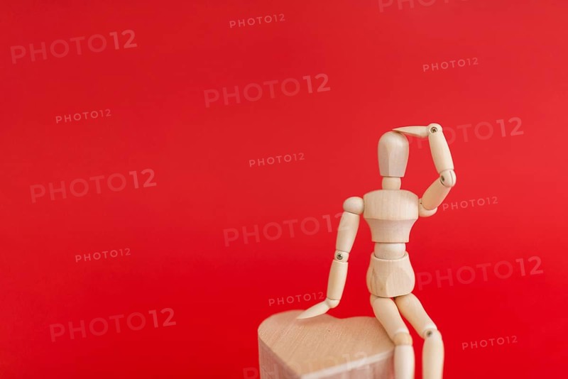 Wooden mannequin sitting wooden heart