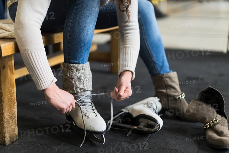 Crop woman putting ice skates