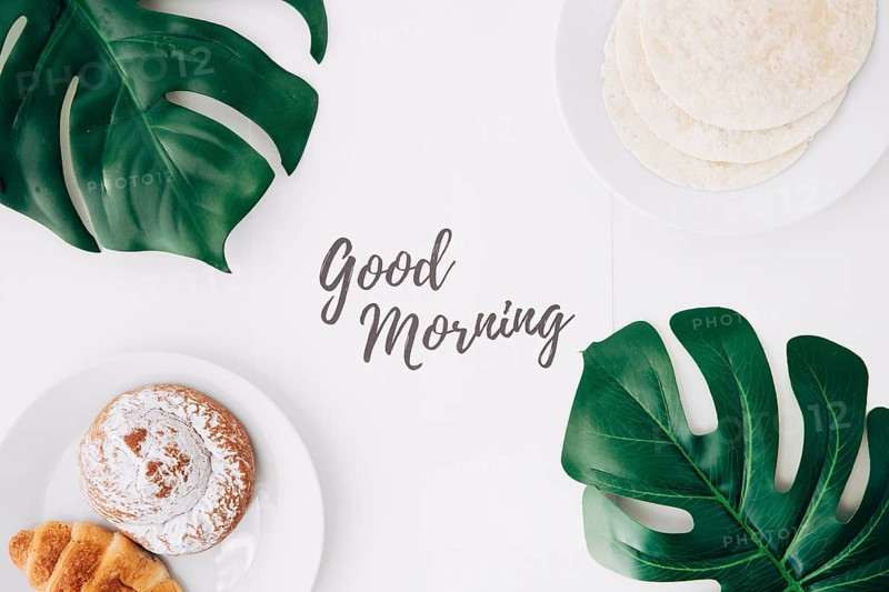 Fresh flour tortillas baked bun croissant breakfast with good morning text paper green monster leaves white background