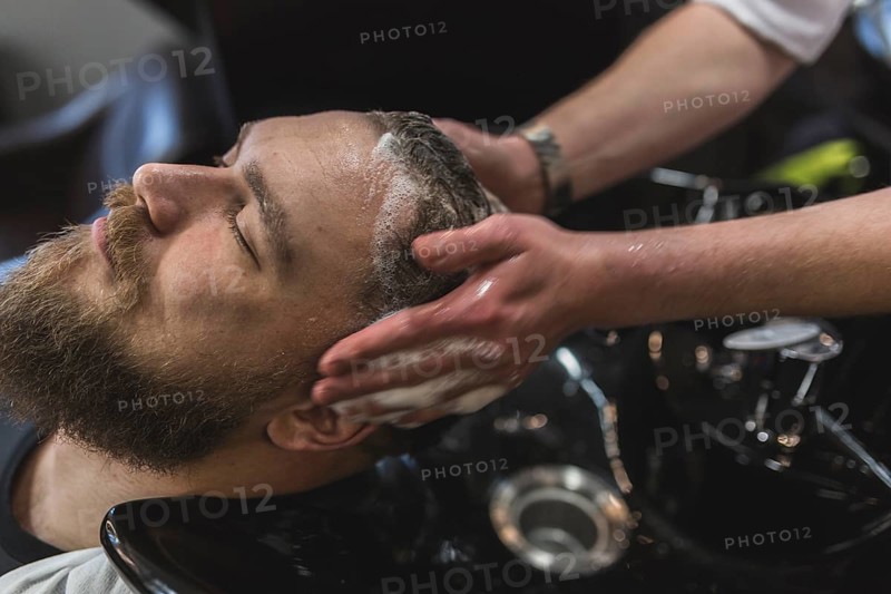 Crop hairdresser washing hair client