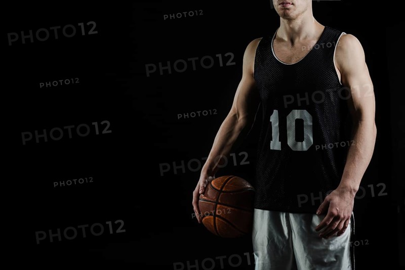 Professional basketball player holding ball his arm