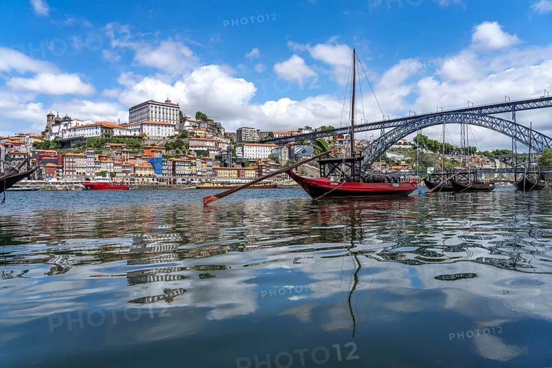 View over the traditional Rabelo boats on the Douro riverbank in Vila Nova de Gaia towards the old town of Porto and the bridge Ponte Dom Luis I