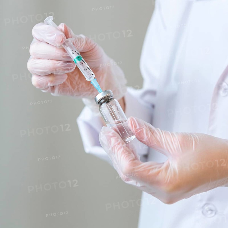Side view female researcher with gloves holding syringe