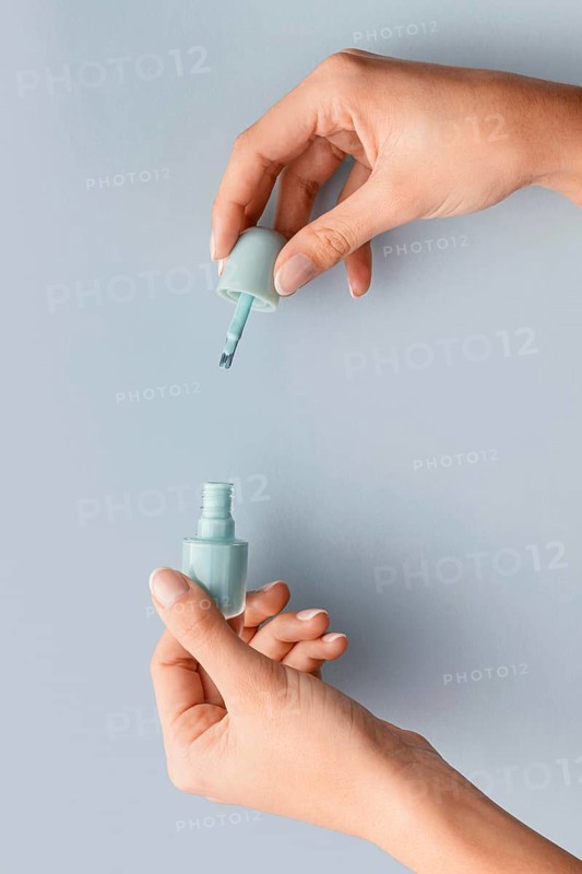 Close up hands holding blue nail polish