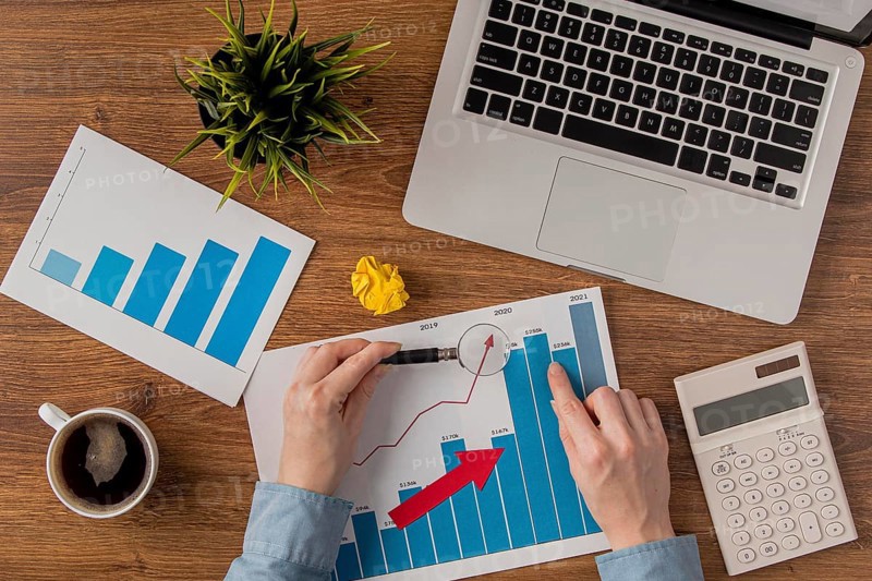 Top view office desk with laptop growth chart analyzed by hands