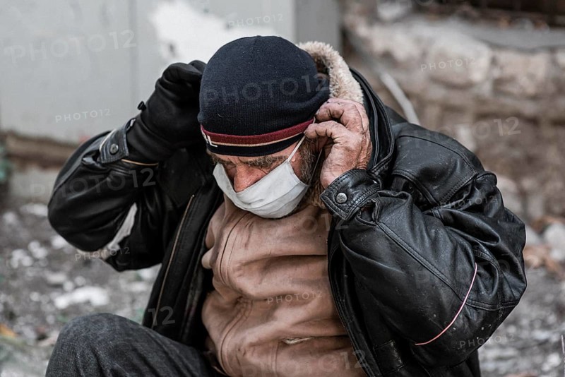 Front view homeless man outdoors putting medical mask