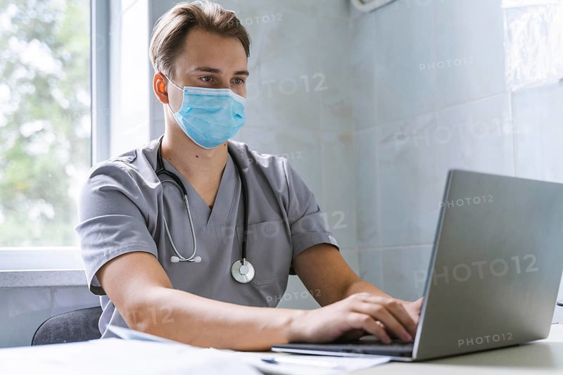 Doctor with stethoscope medical mask working laptop