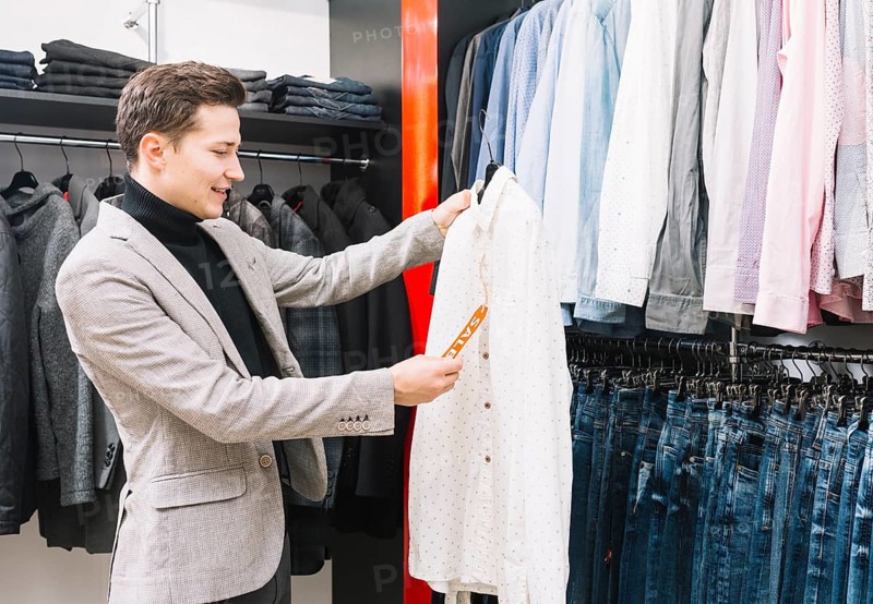 Young man shop checking price tag shirt