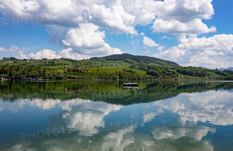 (Cumulus) clouds with fishing boat reflected in the Irrsee, Zell am moss, Salzkammergut, Upper Austria, Austria, Europe