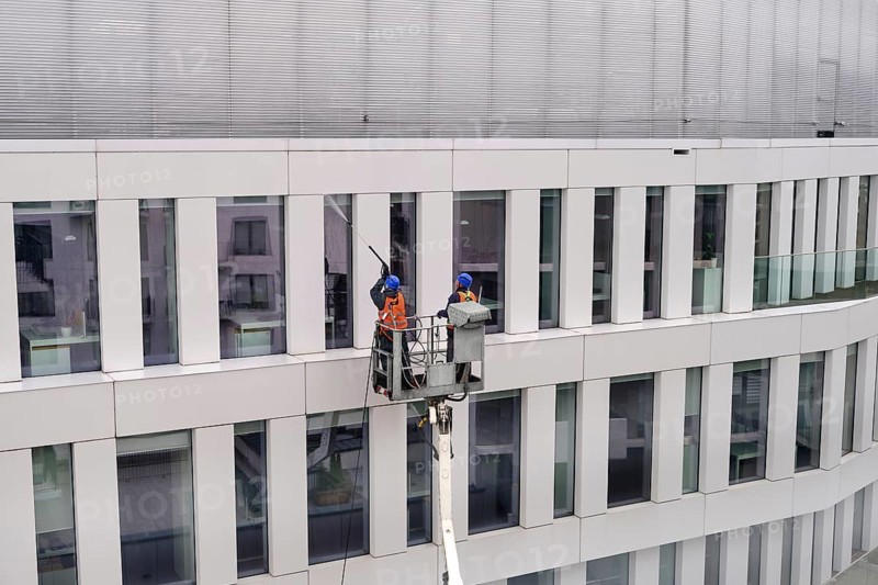 Two workers wearing safety harness wash walls