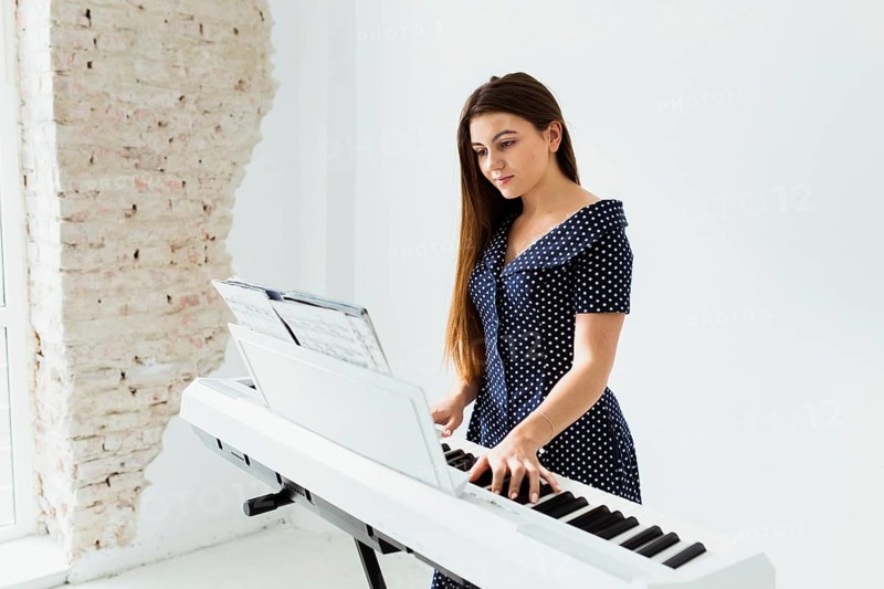 Portrait young woman looking musical sheet playing piano