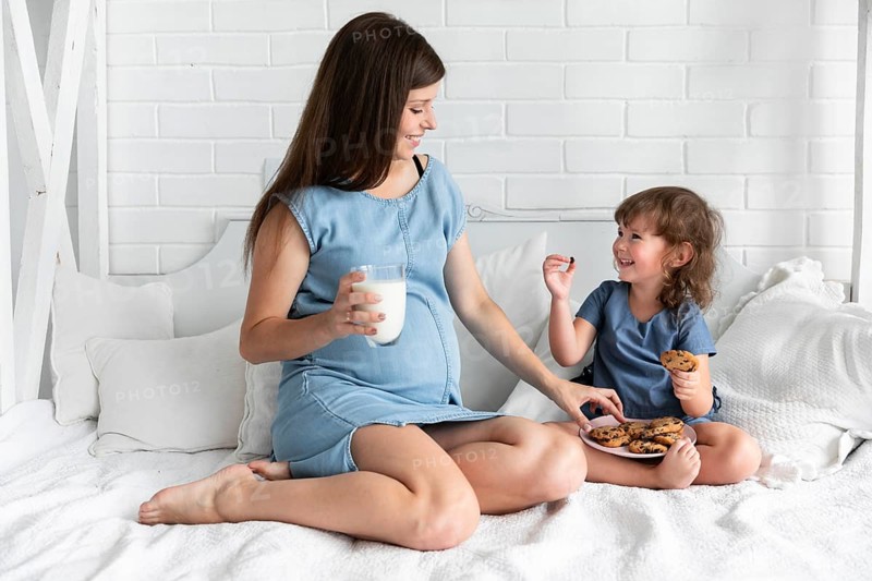 Long shot mother daughter eating chocolate cookies