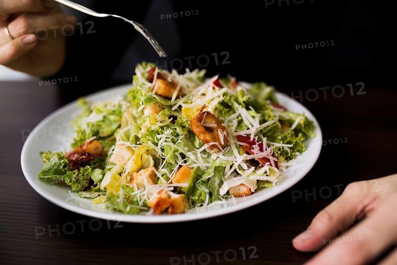 Person eating tasty caesar salad with croutons restaurant