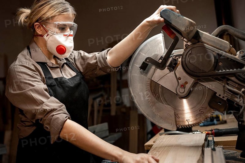 Side view female carpenter using round saw
