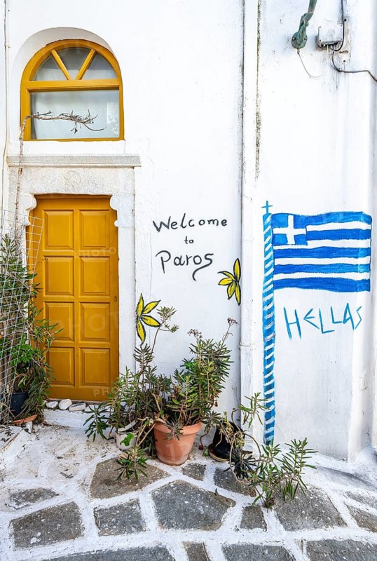 Painted house wall with inscription Welcome to Paros and Hellas with Greek flag