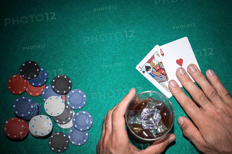 Poker player showing jack ace card with casino chips green poker table