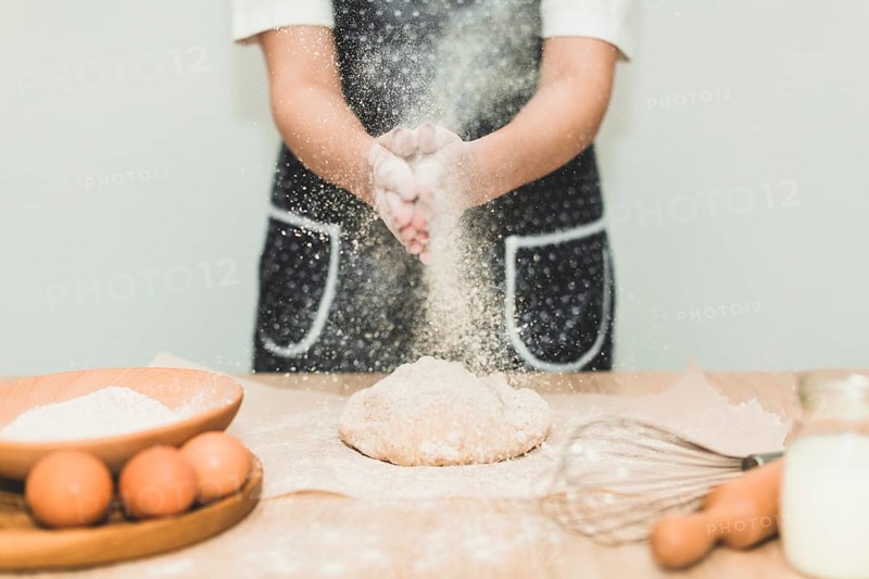 Woman making bread pouring flour