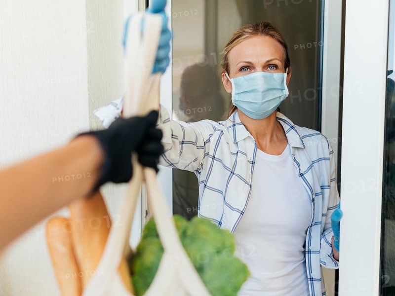 Woman with medical mask home picking up her groceries self isolation