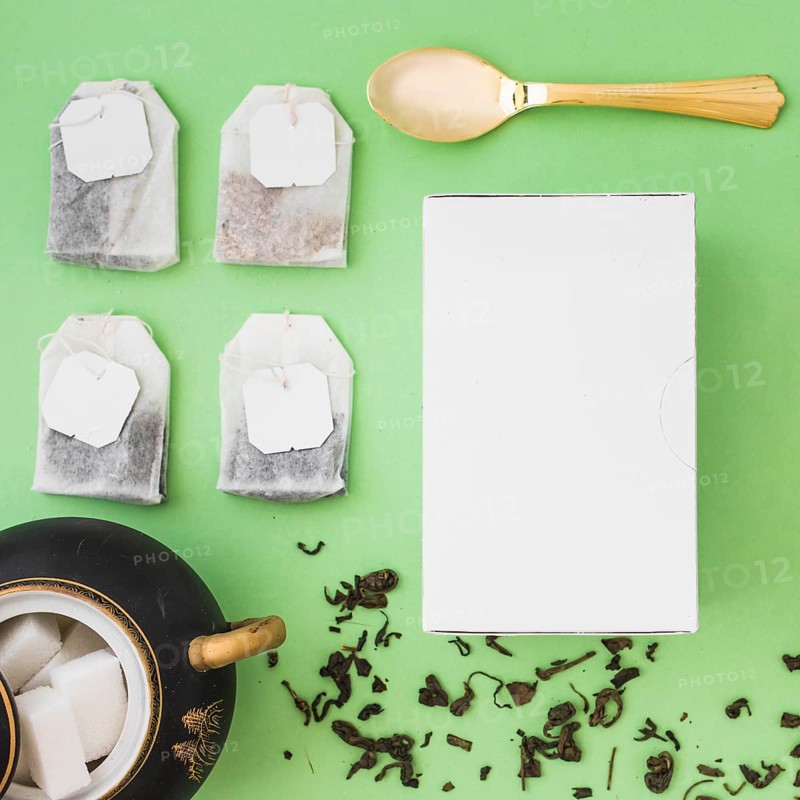 Different type herbal tea bags sugar cubes spoon white box colored background
