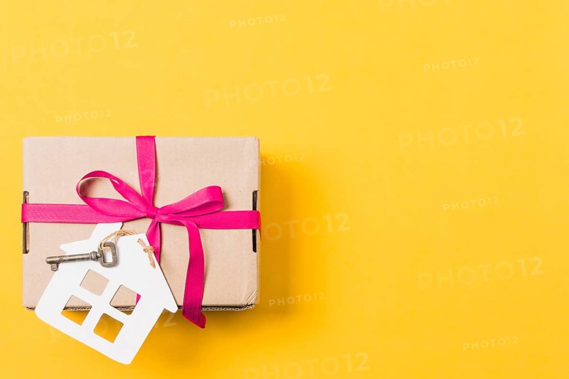 Gift box tied with key house model bright yellow background