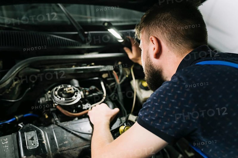 Repairmen inspecting vehicle engine