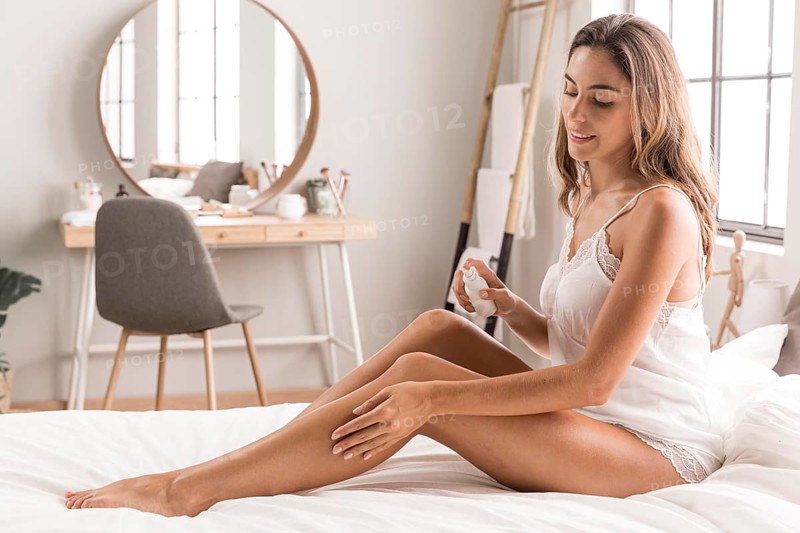 Woman sitting bed massaging her legs