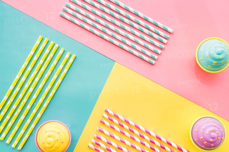 Colored surface with birthday cupcakes straws