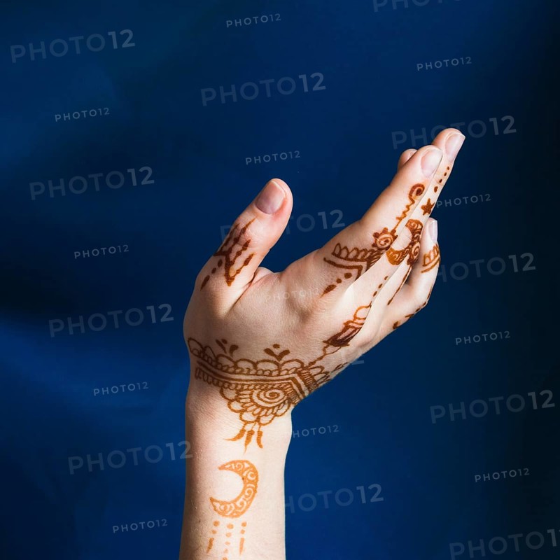 Hand with mehndi near blue textile