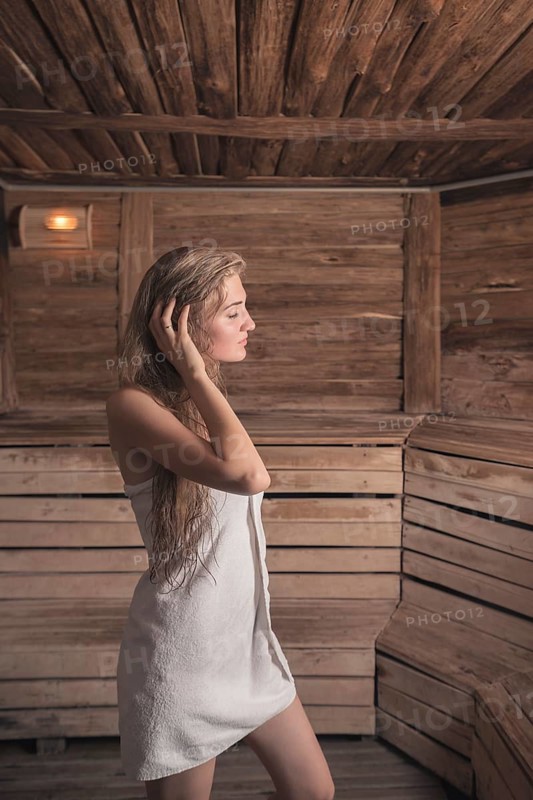 Woman with wet long hair standing hot sauna