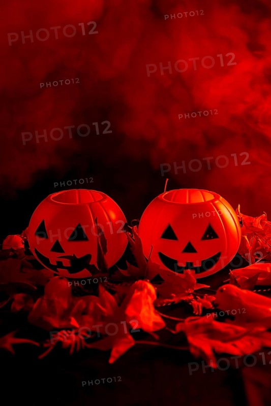 Halloween pumpkins on autumn leaves with smoke on a red background