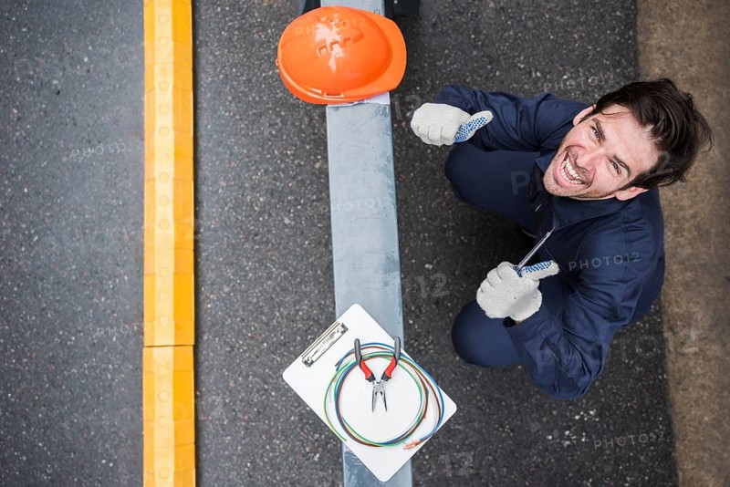 High angle view happy male electrician showing thumb up workplace