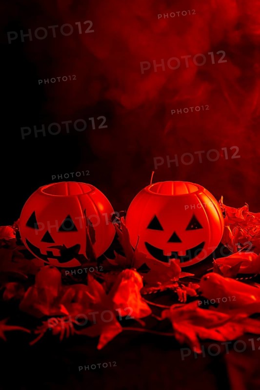 Halloween pumpkins on autumn leaves with smoke on a red background
