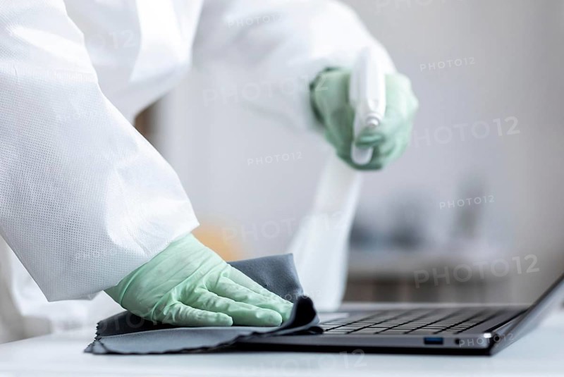 Person disinfecting dangerous area while wearing protective suit
