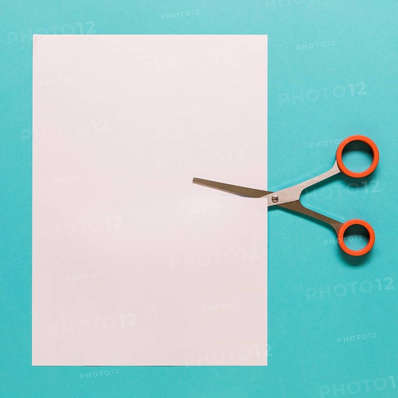 Scissors cutting paper blue background