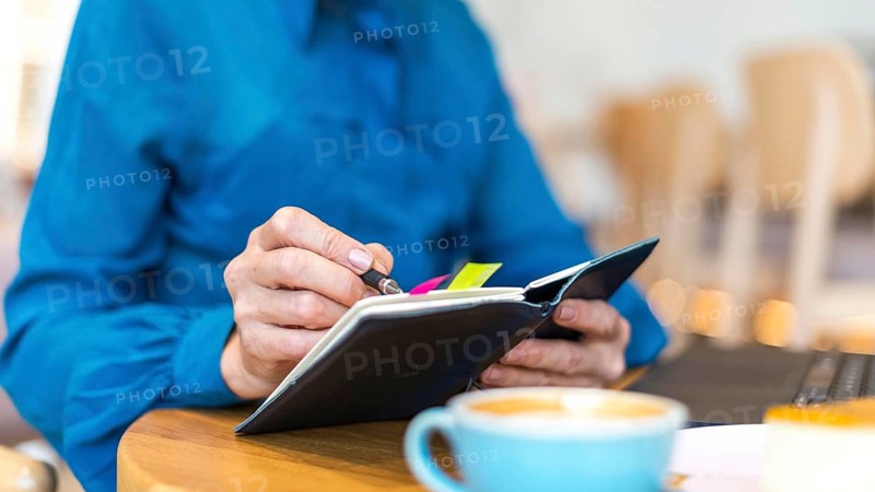 Older business woman working laptop writing agenda