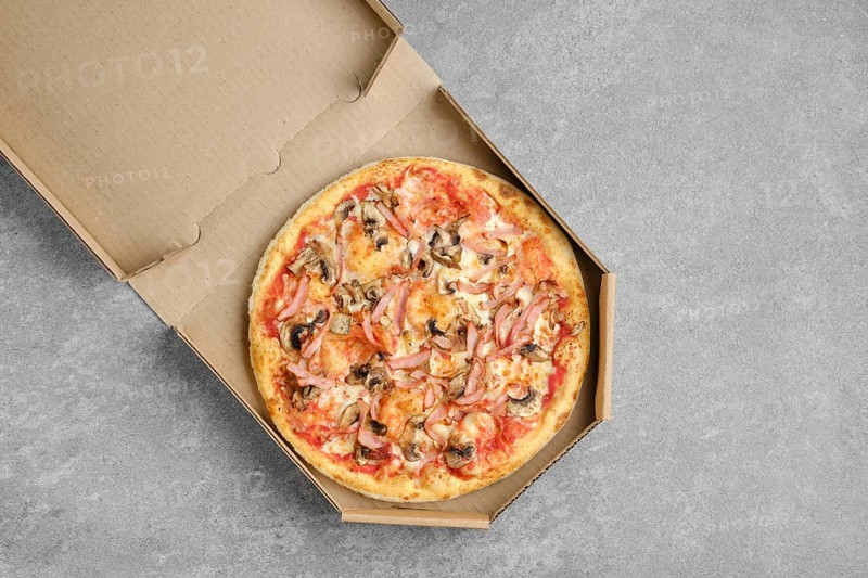 Pizza with ham and champignon mushrooms in cardboard box