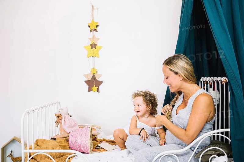 Cheerful pregnant mother baby bed