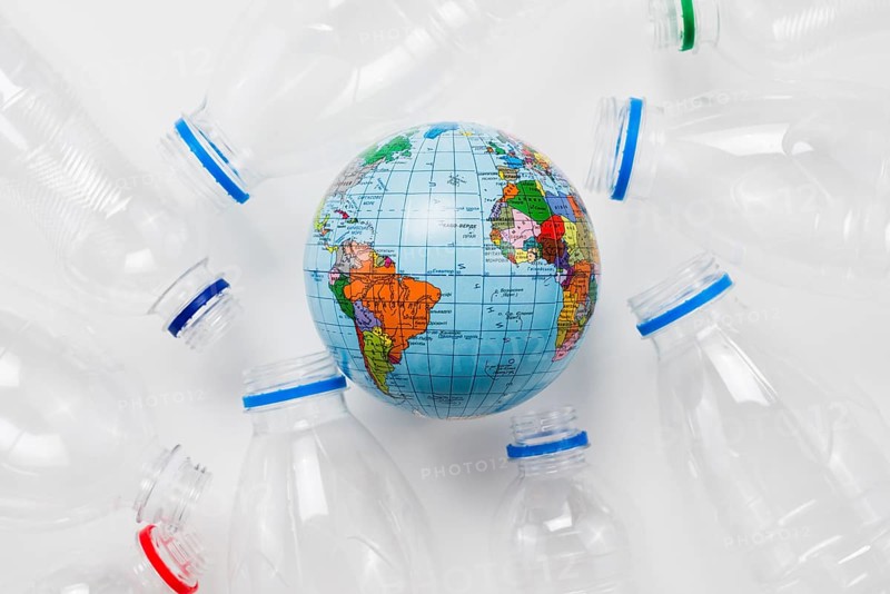 Earth globe surrounded plastic bottles grey table