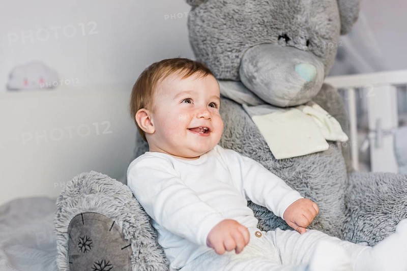 Cute blonde baby white bed with teddy bear