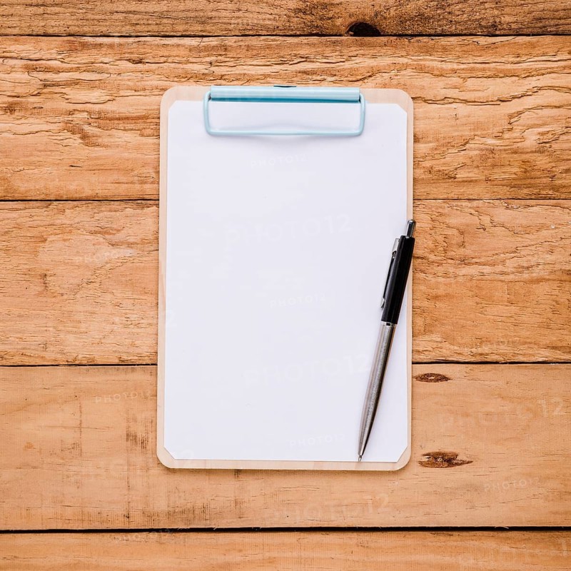 Blank paper clipboard with ballpoint pen wooden desk