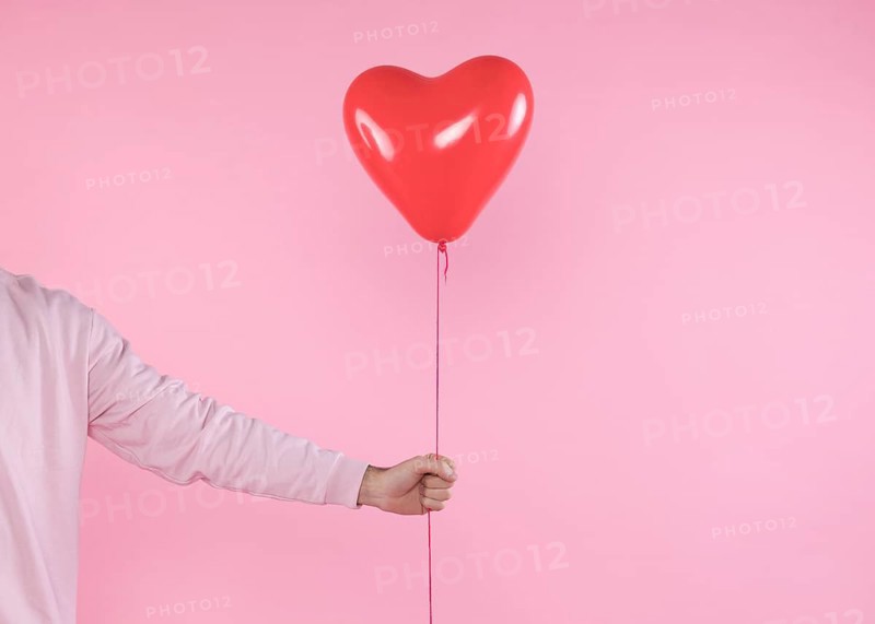 Person holding red balloon with twist