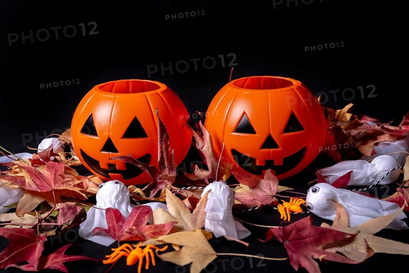 Halloween pumpkins on red autumn leaves and ghosts on a black background