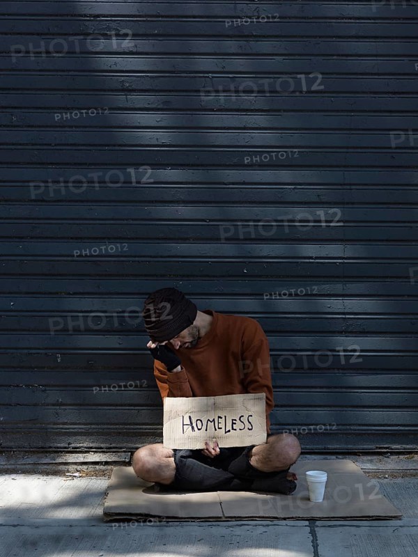 Homeless man hiding his face asking money long view