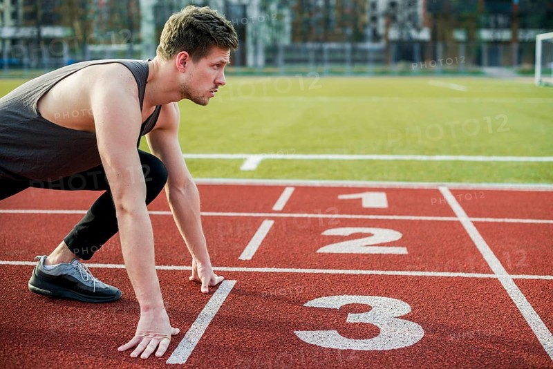 Young male athlete ready run taking position start line