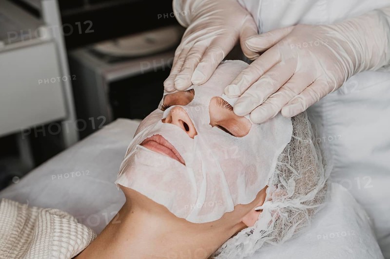 Young woman getting skin mask treatment spa