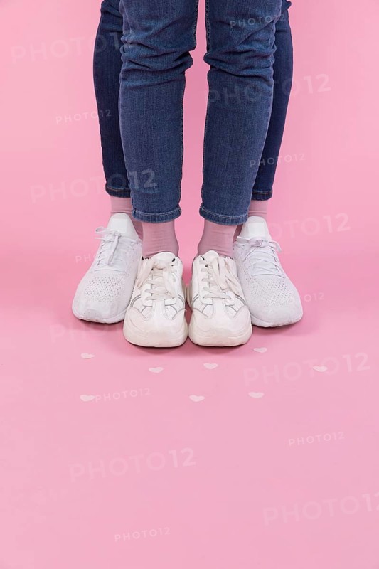 Man woman legs jeans sneakers near decorative hearts