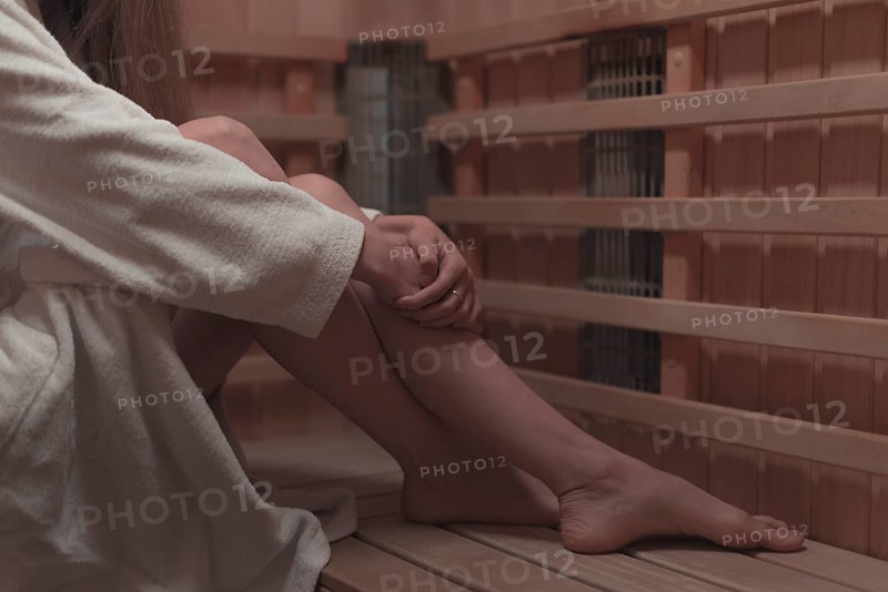 Low section woman sitting wooden bench sauna