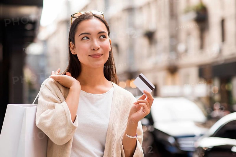 Woman outdoors holding credit card shopping bag