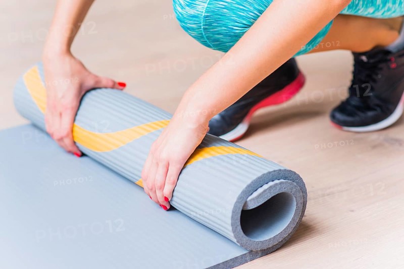 Close up female hand folding yoga mat