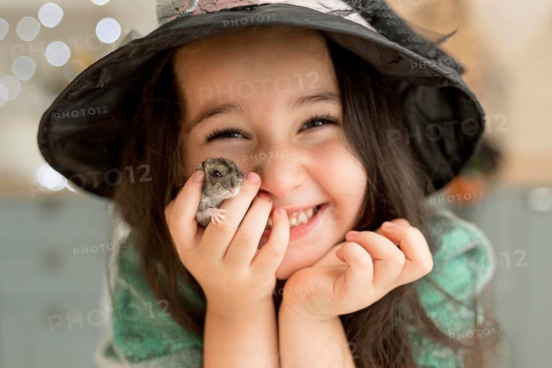 Close up view cute little girl holding hamster